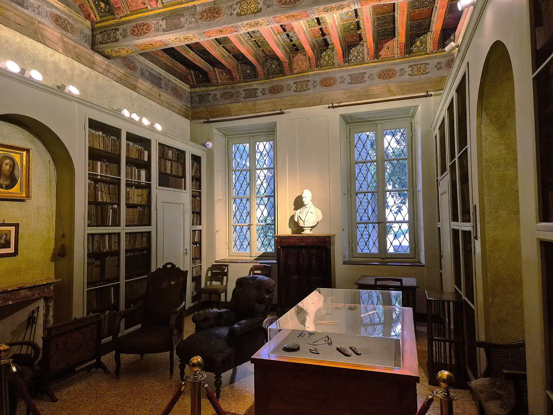 Nell'immagine, l'interno di una stanza della casa di Alessandro Manzoni a Milano: si vede una scrivania con due poltrone e un busto di Manzoni in fondo alla stanza, tra due finestre.